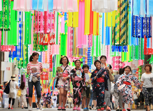 Entre o público, pessoas vestidas de yukata e famílias com crianças, aproveitando as férias de verão