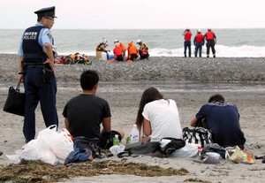 Amigos das vítimas acompanham as buscas na praia. Foto: Chunichi