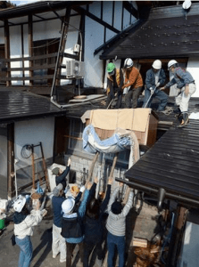 Moradores ajudam a resgatar um armário de uma casa. Foto: Sankei
